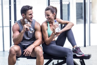 Muscular couple discussing on the bench and holding water bottle.jpeg