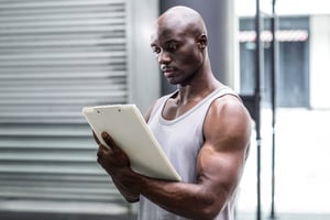 Side view of a muscular trainer writing on clipboard.jpeg